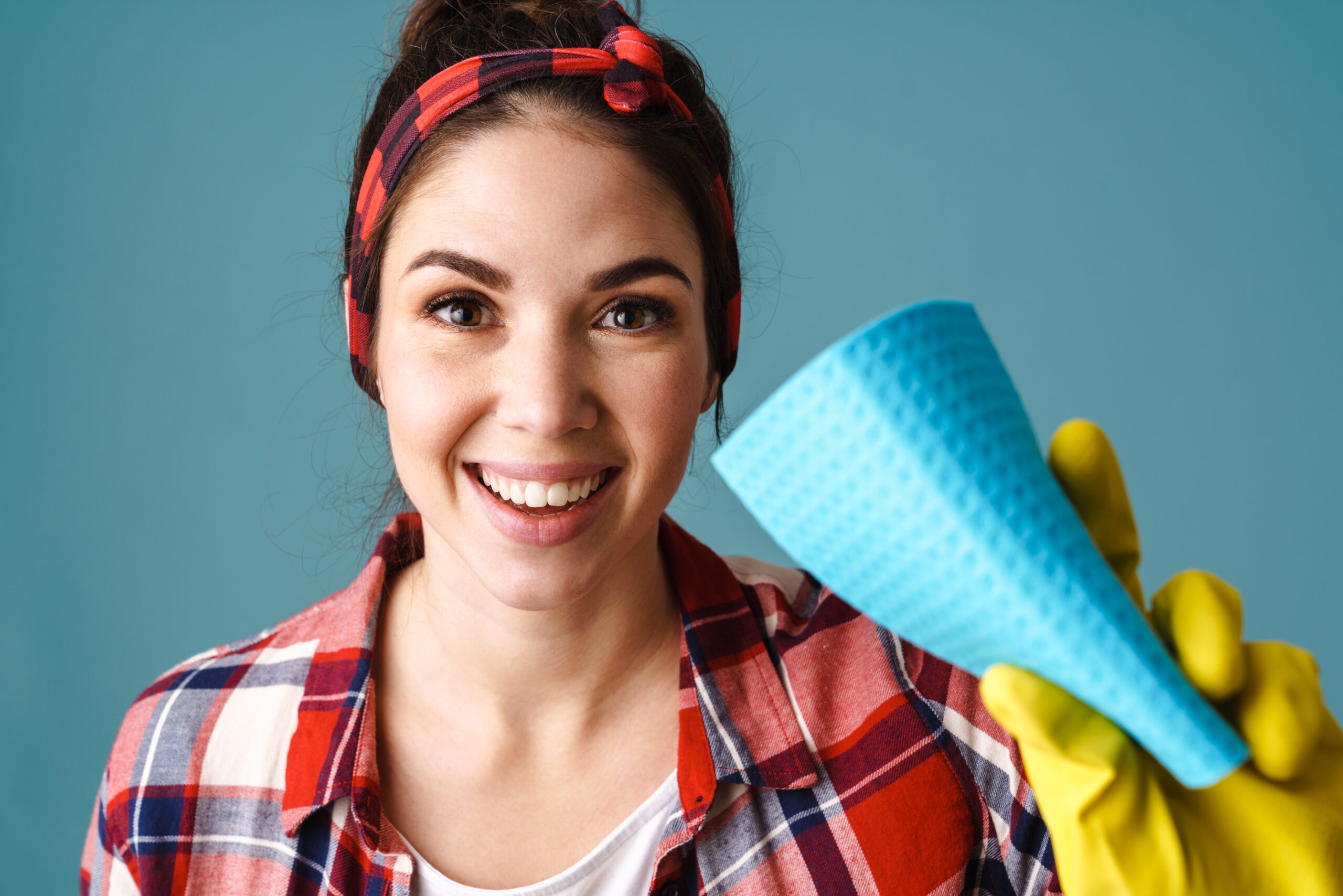happy young woman in gloves smiling and showing washcloth