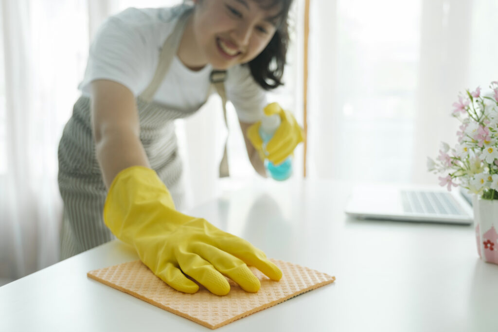 young woman cleaning table wearing gloves at home.